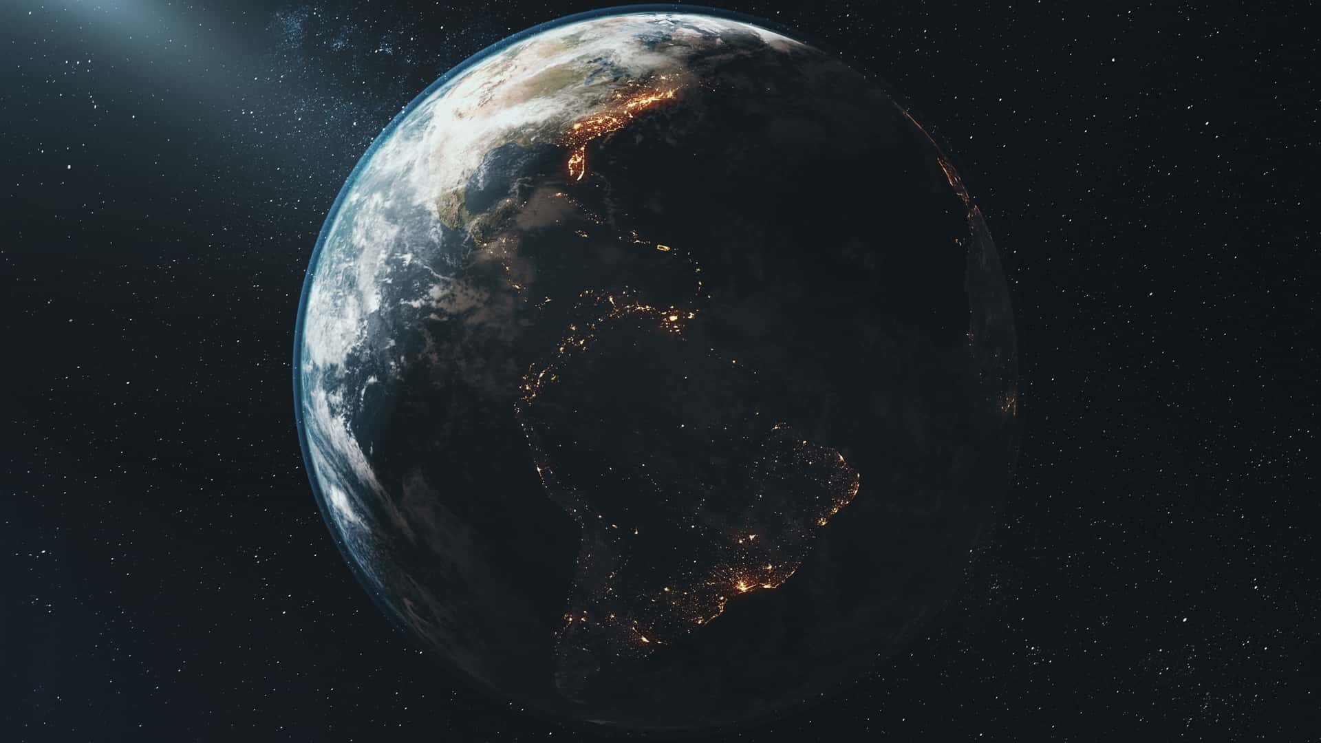 Earth at night, seen from space, with city lights tracing the coastlines of the Americas.